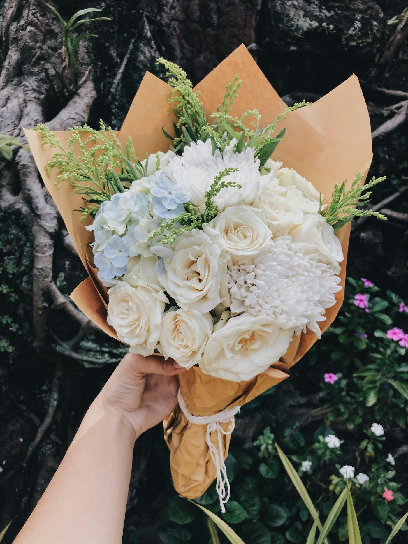 A hand tied bouquet of cream and white roses
