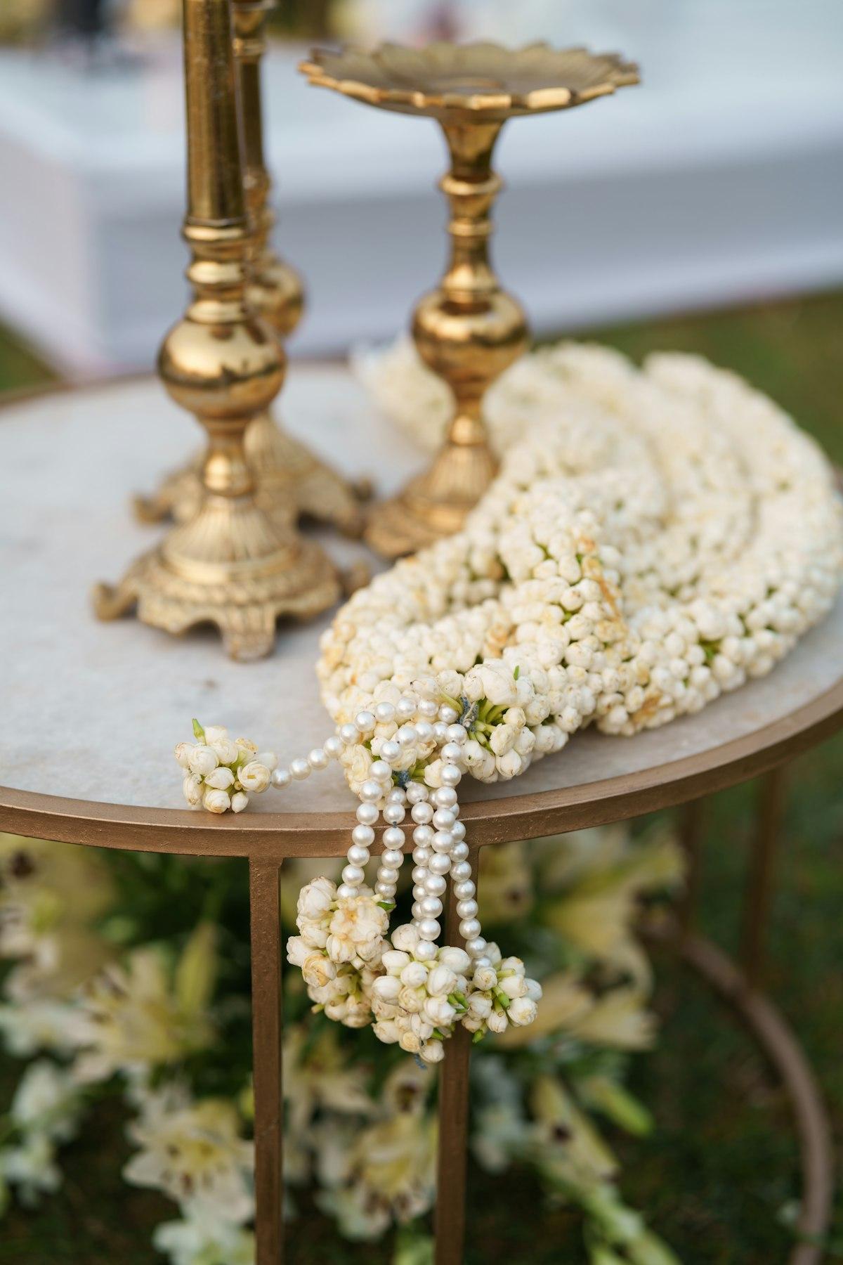 A jasmine flower garland with pearl detailing laid out on a table