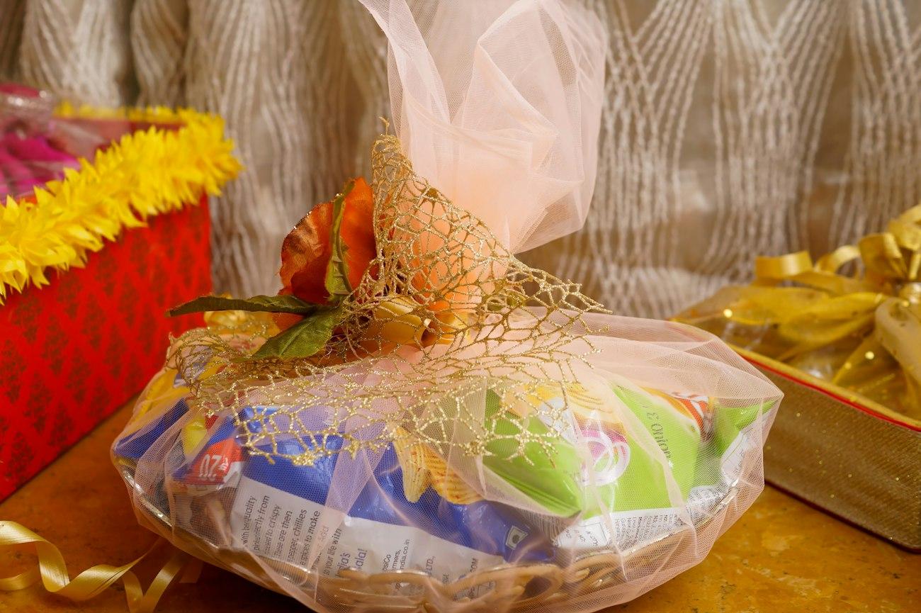 A wicker hamper wrapped in net and gold mesh, finished with a flower