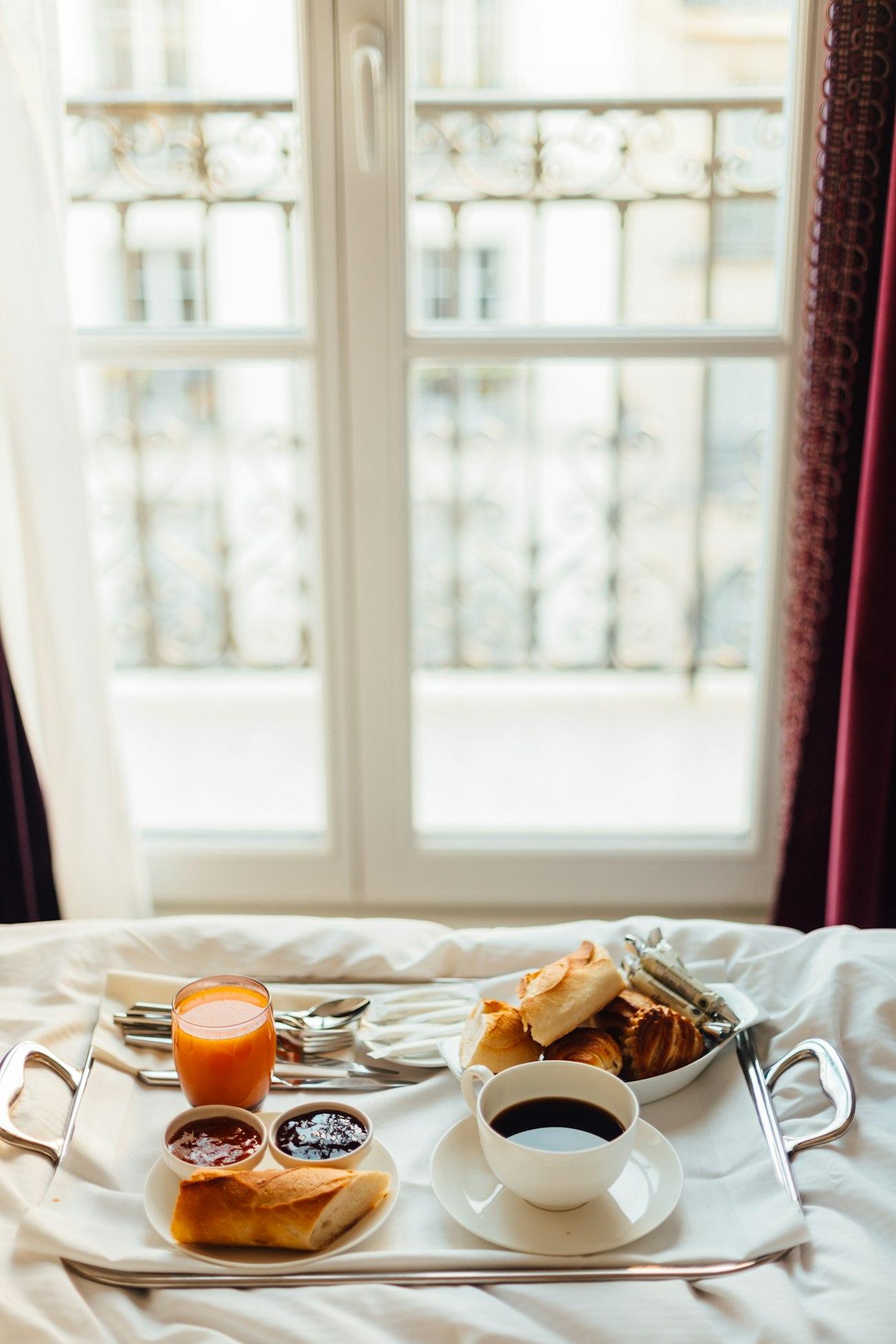 A breakfast tray with coffee set out on a bed